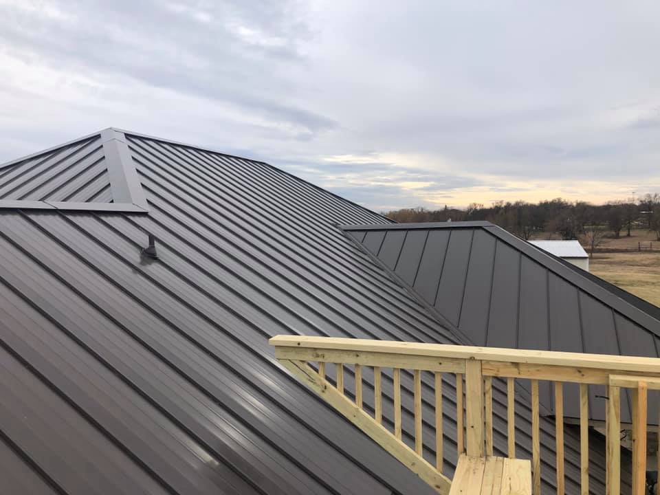 Completed dark standing-seam metal roof with new deck railing