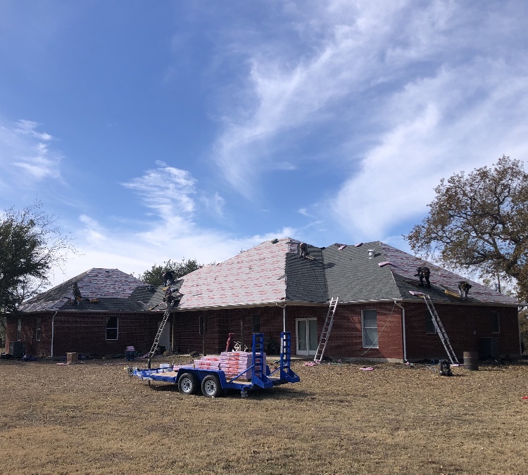 Crew replacing the roof on a large brick home